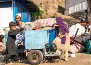 A family sit beside their belongings after crossing into Afghanistan from Pakistan. (Photo UNHCR/Oxygen Empire Media Production)