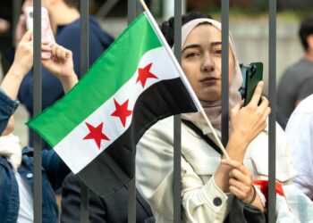 A woman holds the new Syrian flag outside UN Headquarters in New York. (UN Photo/Mark Garten)