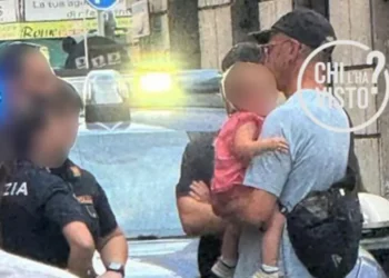 Rexal Ford holding the baby in a street in Rome on June 5, surrounded by police officers responding to a call about a crying child. The photo was released by the TV program Chi l’ha visto?