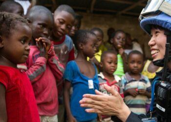 A Chinese police officer deployed to the UN Mission in Liberia (UNMIL), talks to a young girl whilst on patrol. The Mission completed its mandate in March 2018. (UN Photo/Albert González Farran )